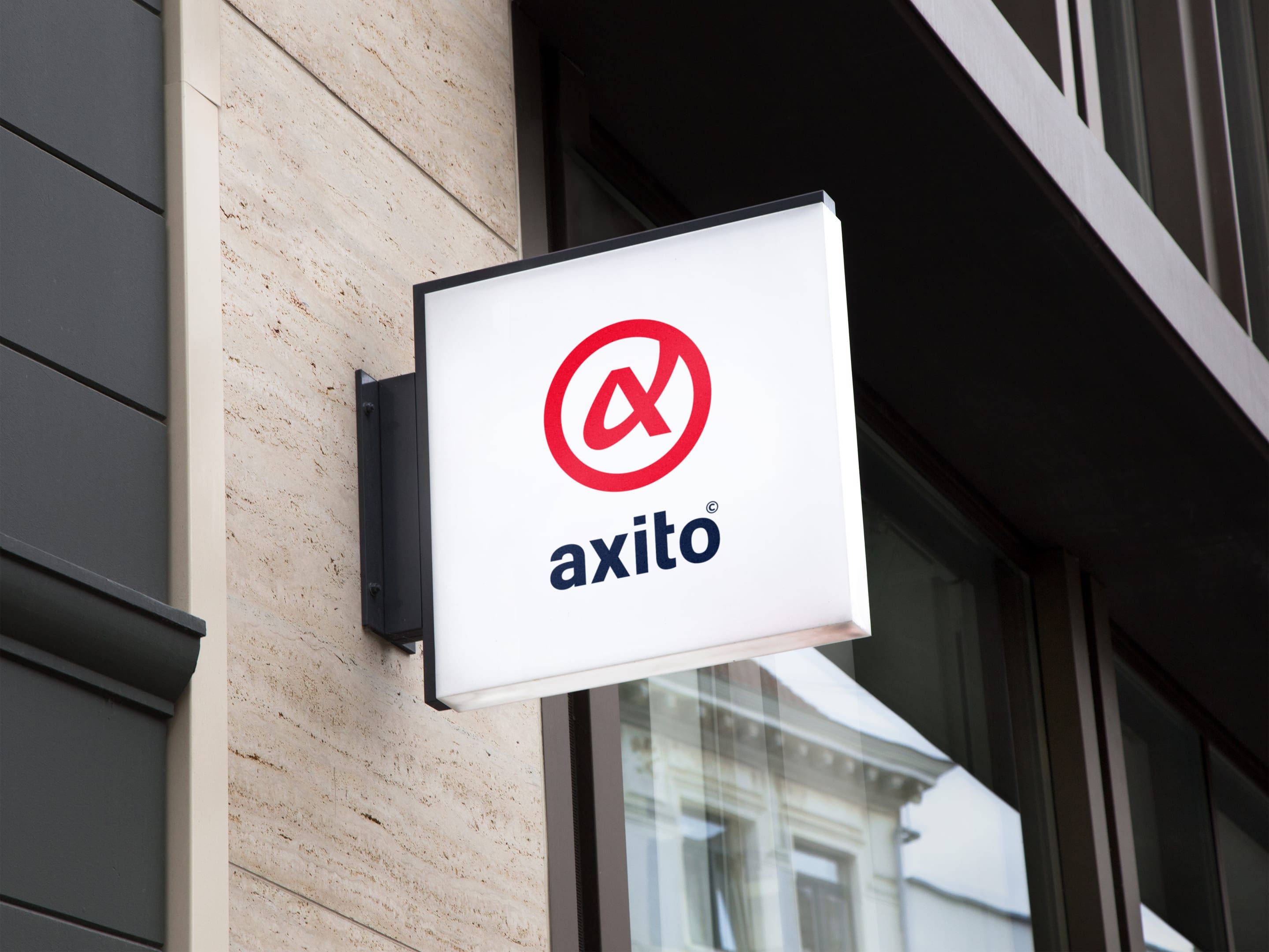 Axitos ljusskylt på en fasad: ett rött @-tecken över namnet