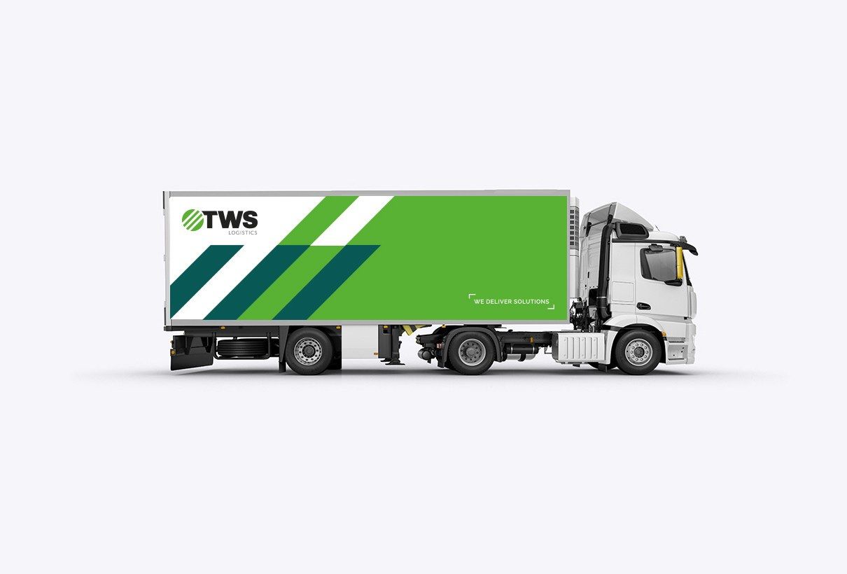 En lastbil med vit skåpkropp, foliering med gröna och blå band och logotypen TWS